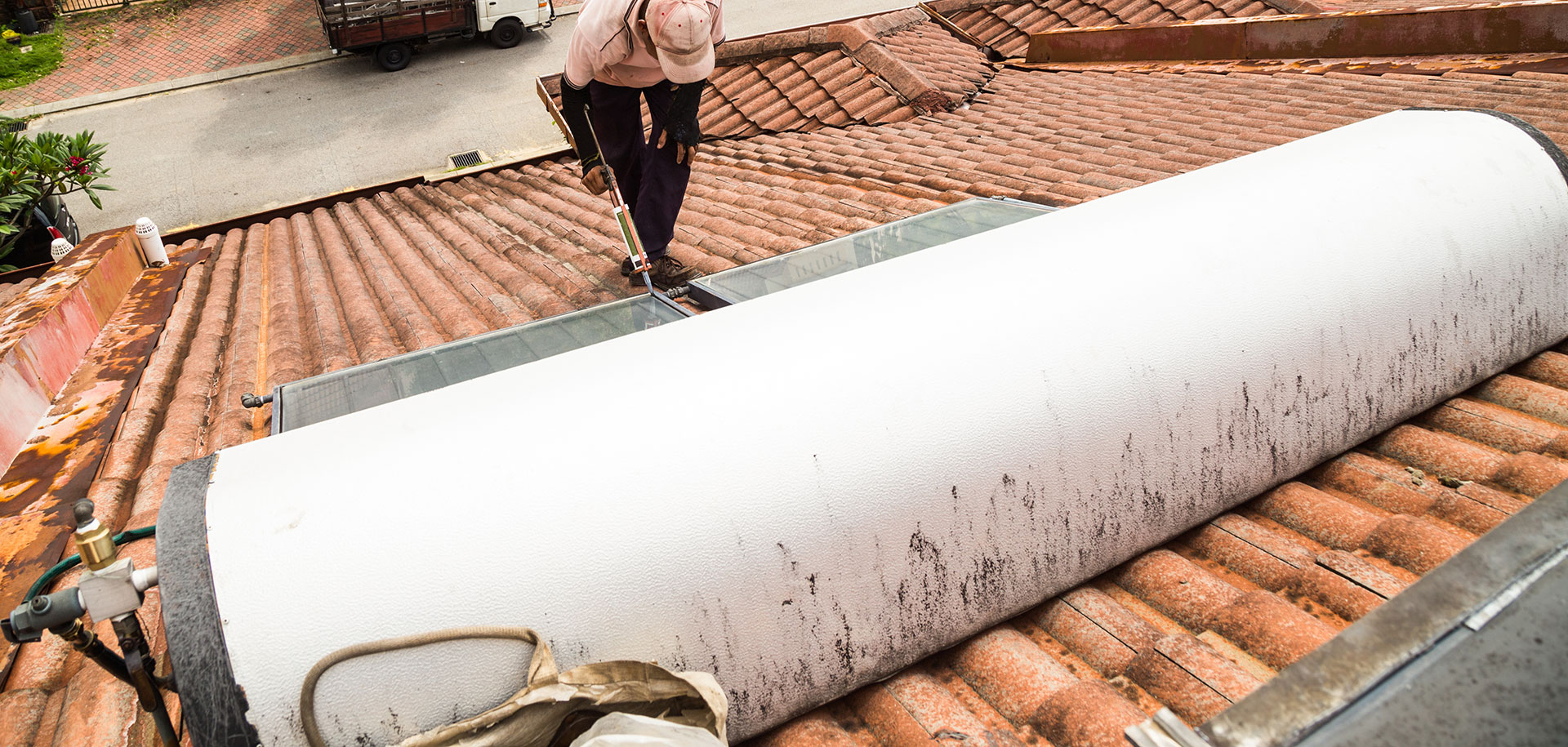 worker fixing solar water heater on roof