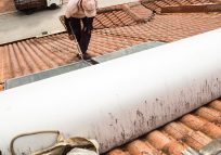 worker fixing solar water heater on roof